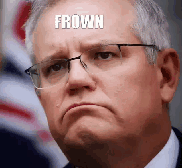a man wearing glasses and a suit is making a funny face with the word frown on his forehead .