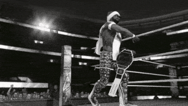 a black and white photo of a wrestler holding a wrestling championship belt