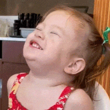 a little girl is laughing with her eyes closed