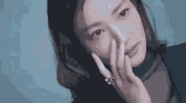 a close up of a woman covering her face with her hands .