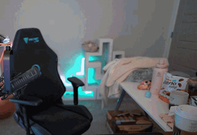 a black gaming chair sits in a messy room