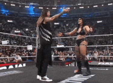 a man and woman are hugging in a wrestling ring .