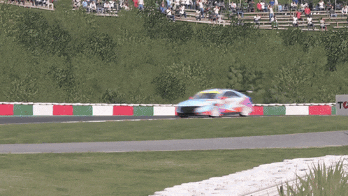 a race car is going around a curve on a track with trees in the background