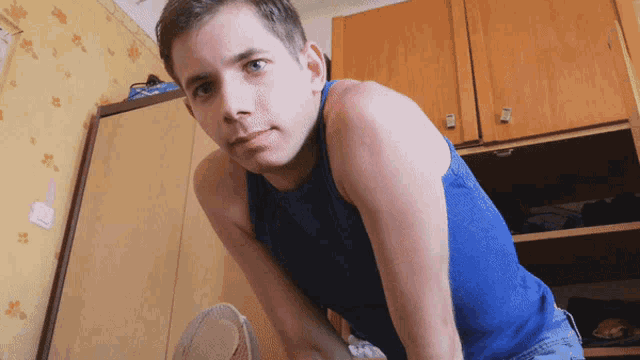 a man in a blue tank top is kneeling down