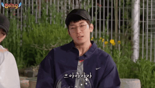 a man wearing glasses and a nike jacket talks to someone