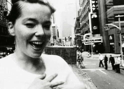 a black and white photo of a woman laughing in the street .