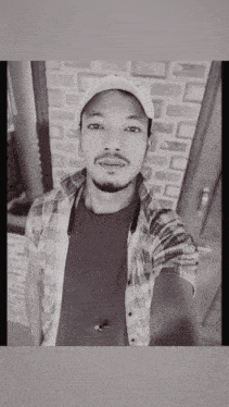a man wearing a plaid shirt and a white hat takes a selfie