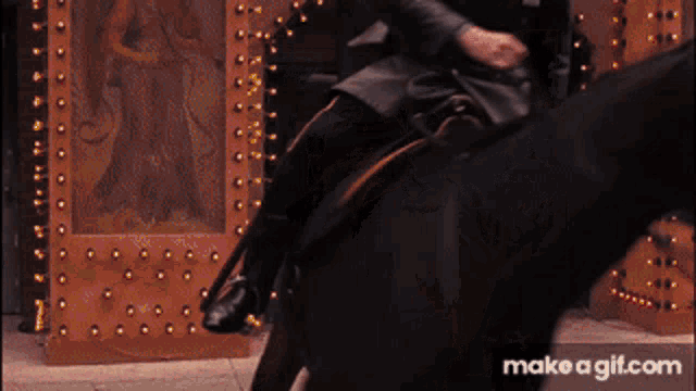 a man is riding a horse in front of a door that says make a gif.com on the bottom