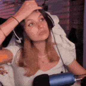 a woman wearing headphones is sitting in front of a microphone and touching her forehead .