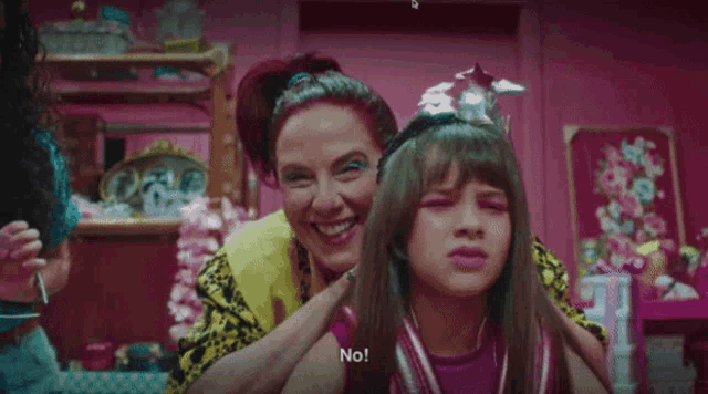 a woman is putting a crown on a little girl 's head