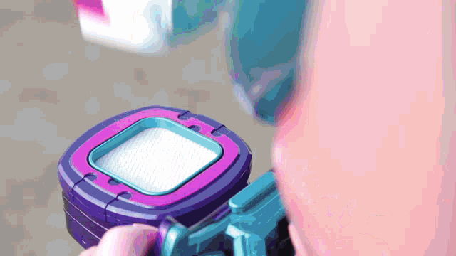 a person is holding a purple and blue device that looks like a video game