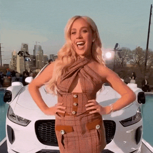 a woman in a plaid dress is standing in front of a car