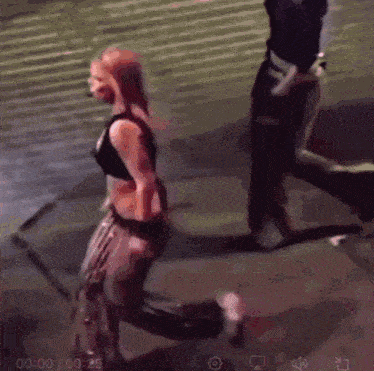 a woman in a black top is kneeling down in front of a man in a black jacket