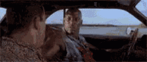 two men are sitting in a car and talking .