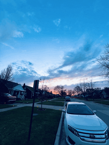 a white ford car is parked on the side of a street