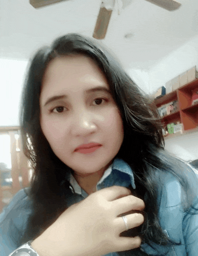 a woman wearing a watch and a ring takes a selfie