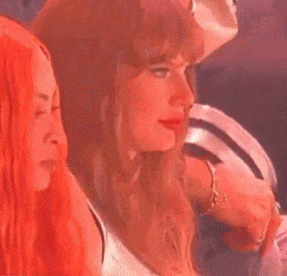 a woman is sitting in a crowd of people at a concert and looking at something .