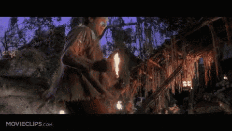 a man with paint on his face is holding a torch in the dark .