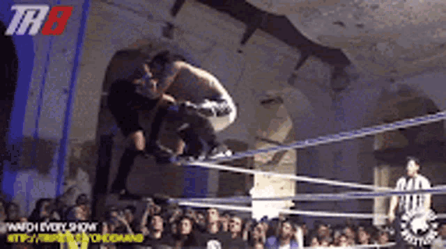two wrestlers are fighting in a ring with the letters thb on the wall