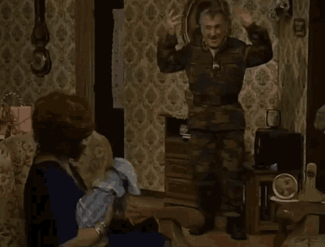a man in a camouflage uniform is standing in front of a woman in a chair