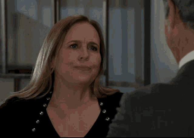 a woman with a sad look on her face is talking to a man in a suit