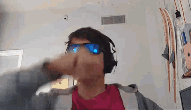 a man wearing headphones and sunglasses is making a funny face in a room .