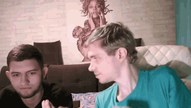 two men are sitting in front of a painting of medusa on the wall
