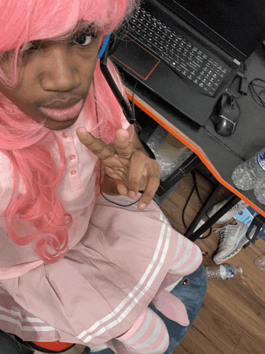 a man in a pink wig is sitting in front of a lenovo laptop
