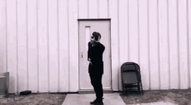 a man in a black suit is standing in front of a door holding a cat .