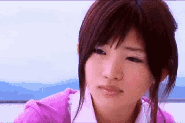 a close up of a woman 's face with a pink shirt on