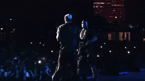 two men singing into microphones with one wearing a hat