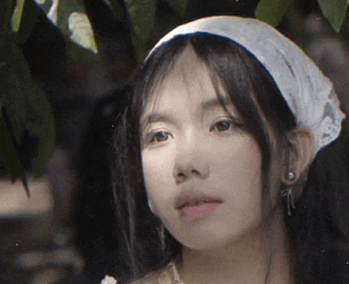 a close up of a woman wearing a white headband and earrings .