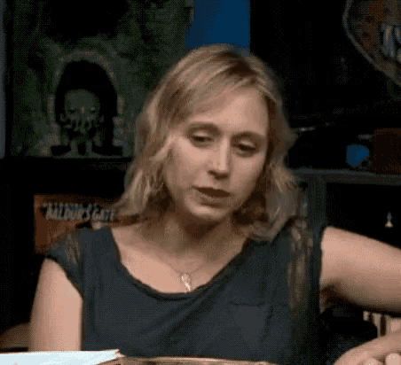 a woman is sitting at a table with a plate of food and a necklace on her neck .