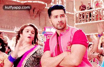 a man and a woman are dancing in a room with their arms crossed .
