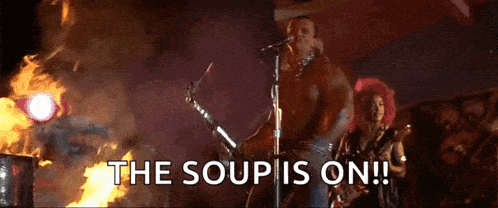 a man without a shirt is playing a guitar and singing into a microphone on a stage .