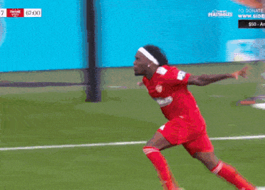 a soccer player wearing a headband and a red shirt is running on the field