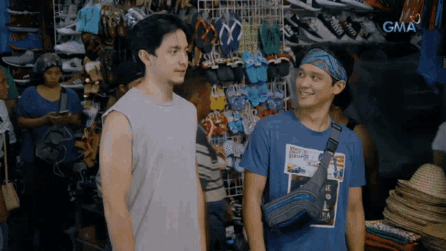two men are standing in front of a store with gma written on the bottom