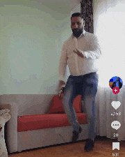 a man is dancing in a living room with a couch in the background