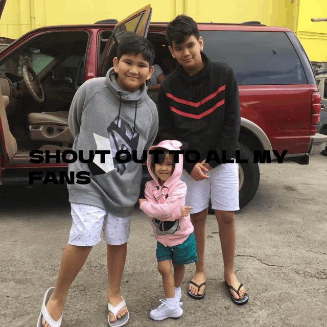 three children standing in front of a red van with the words shout out to all my fans written above them