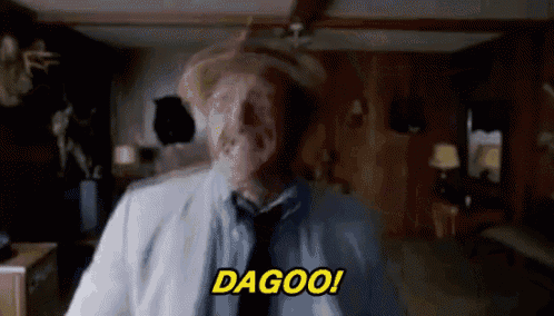 a man in a cowboy hat and tie is standing in a room with the word dagoo written on the screen .