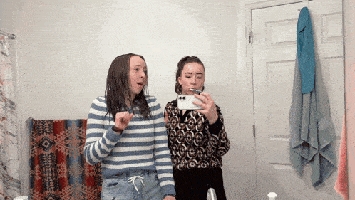 two girls are taking a picture of themselves in the bathroom mirror