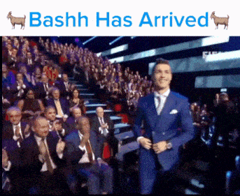 a man in a blue suit is standing in front of a crowd with the words bashh has arrived