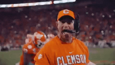 a man wearing a clemson shirt and a hat is on a football field