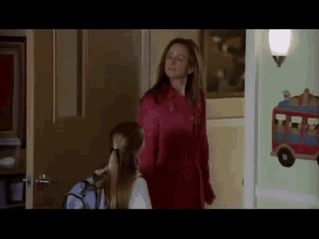 a woman in a red coat is standing next to a girl in a white shirt