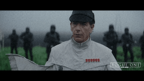 a man in a rogue one star wars uniform stands in front of a group of soldiers