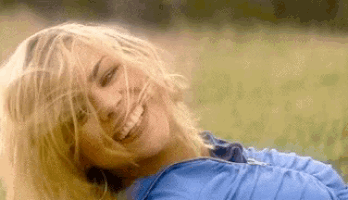 a woman in a blue shirt is smiling in a field .