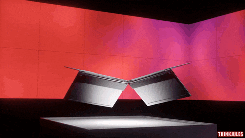 two laptops are floating in the air in front of a red and purple wall with thinkjules written on the bottom