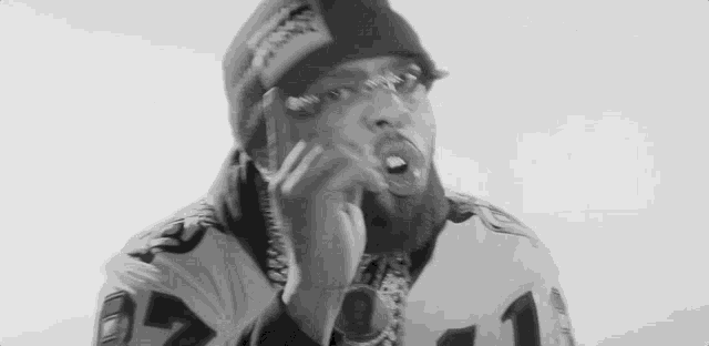 a black and white photo of a man with a beard wearing a beanie and a football jersey .