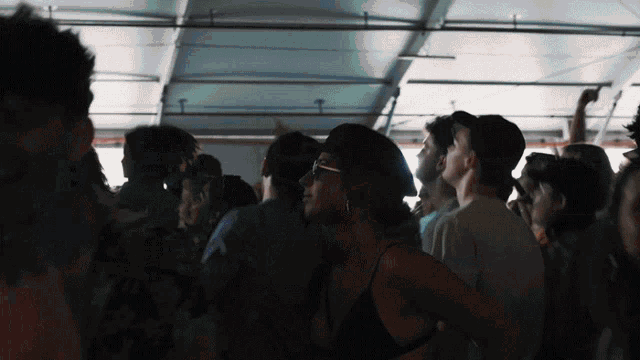 a crowd of people dancing in a dark room with a woman wearing glasses