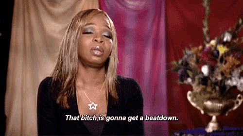 a woman is sitting in front of a vase of flowers and says `` that bitch is gonna get a beatdown '' .